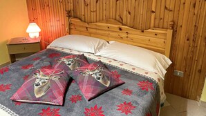 A wooden-paneled room with a bed, pillows, and a nightstand with a lamp. - Casa vacanze - Villa Stefania 1 (Pescocostanzo)