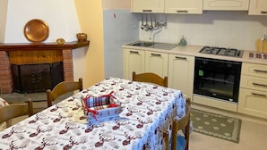 Una cucina con mobili bianchi, un fornello a gas e un forno integrato. C'è un tavolo da pranzo con una tovaglia festosa e un tovagliolo americano a quadri.