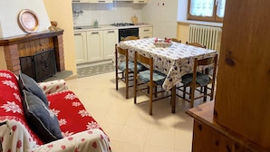 Un ambiente compatto con angolo ristoro, angolo cottura e camino.