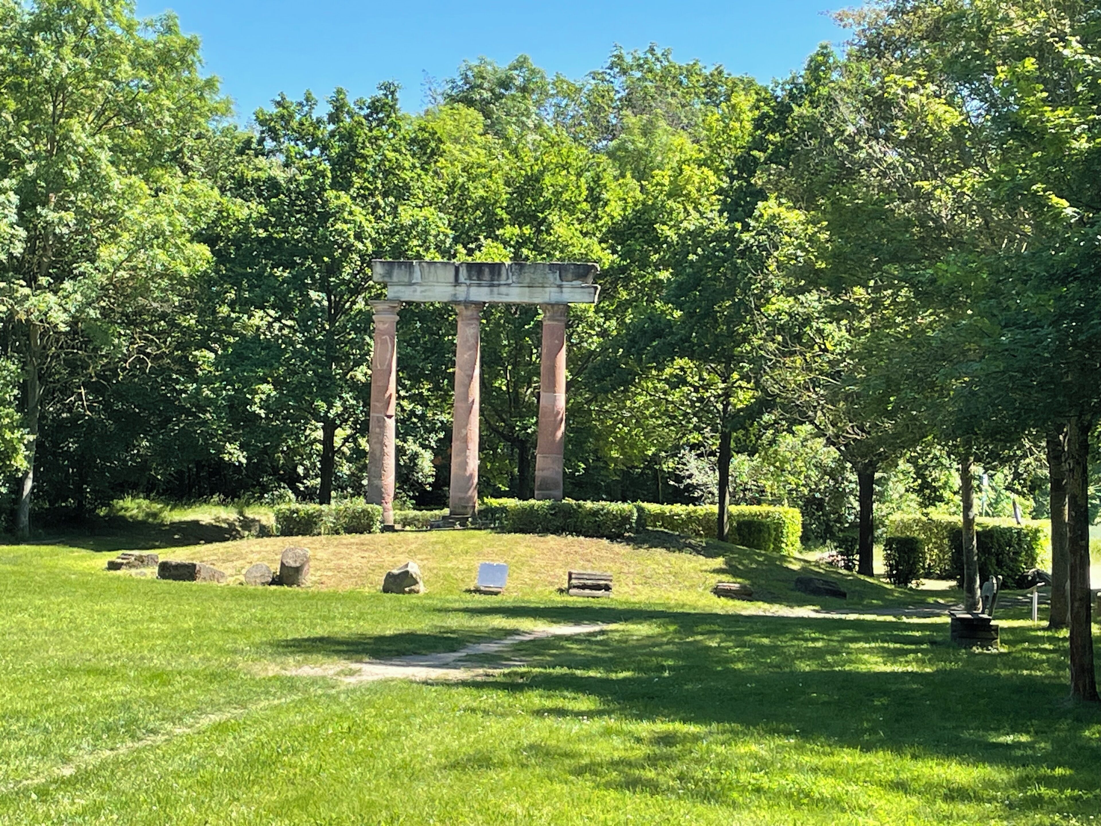 Ein Park mit einer klassischen Architektur, grünem Rasen und Bäumen.