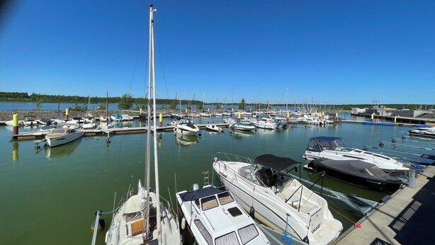 A marina with various boats docked, a clear sky, and calm water.
