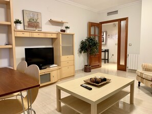 A living room with a TV, wooden furniture, a dining table, and a potted plant. - Central location, parking, next to the train (Cordoba)