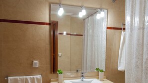 A bathroom with a large mirror, a sink, and two potted plants. - Central location, parking, next to the train (Cordoba)