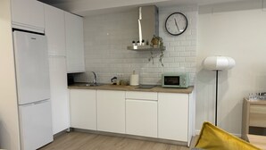 A modern kitchen with white cabinets, a microwave, a sink, and a clock on the wall. - Downtown Loft 16A Córdoba (Cordoba)