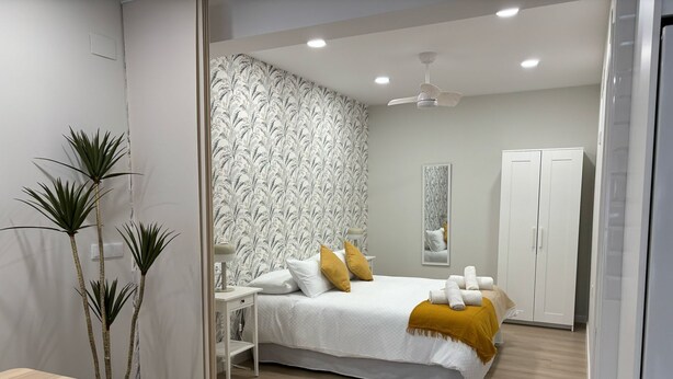 A modern bedroom with a bed, bedside table, lamp, wardrobe, and a dining area with a table and chairs. - Downtown Loft 16A Córdoba (Cordoba)