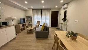 A modern living room with a sofa, a dining table, and a kitchen area with a microwave. - Downtown Loft 16A Córdoba (Cordoba)