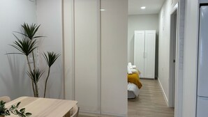 A modern interior with a wooden dining table, a sliding door, and a hallway leading to a bedroom with a bed and a wardrobe. - Downtown Loft 16A Córdoba (Cordoba)