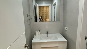Ein Badezimmer mit einem weißen Waschtisch, einem Waschbecken und einem Spiegel.