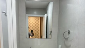Ein Badezimmer mit einem weißen Waschtisch, einem Spiegel und einem Handtuchhalter.