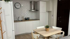 Eine moderne Küche mit weißen Schränken, einer Edelstahl-Spüle und einer Uhr an der Wand.