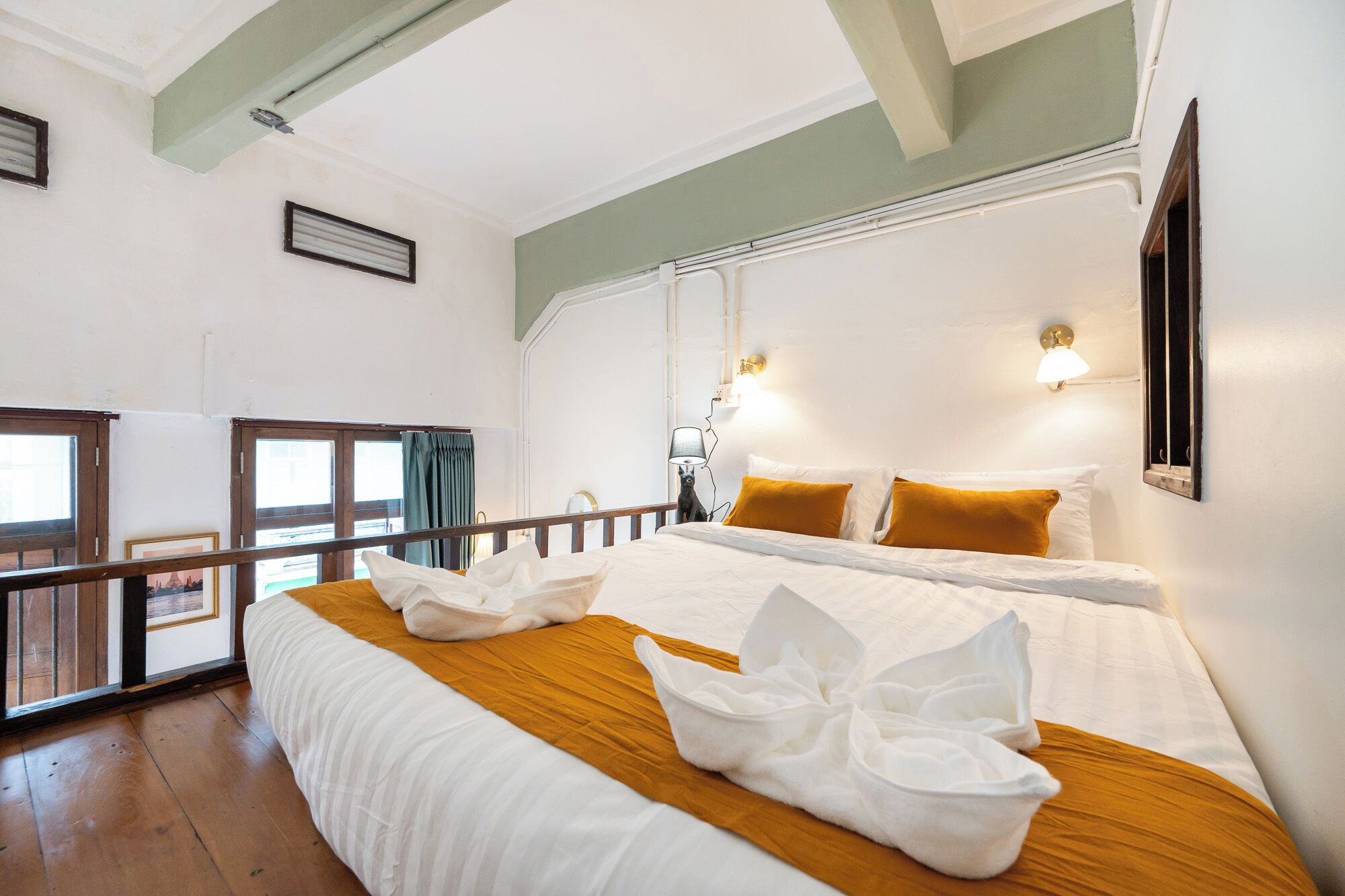 A hotel room with a bed, a nightstand, a lamp, and a window with curtains.