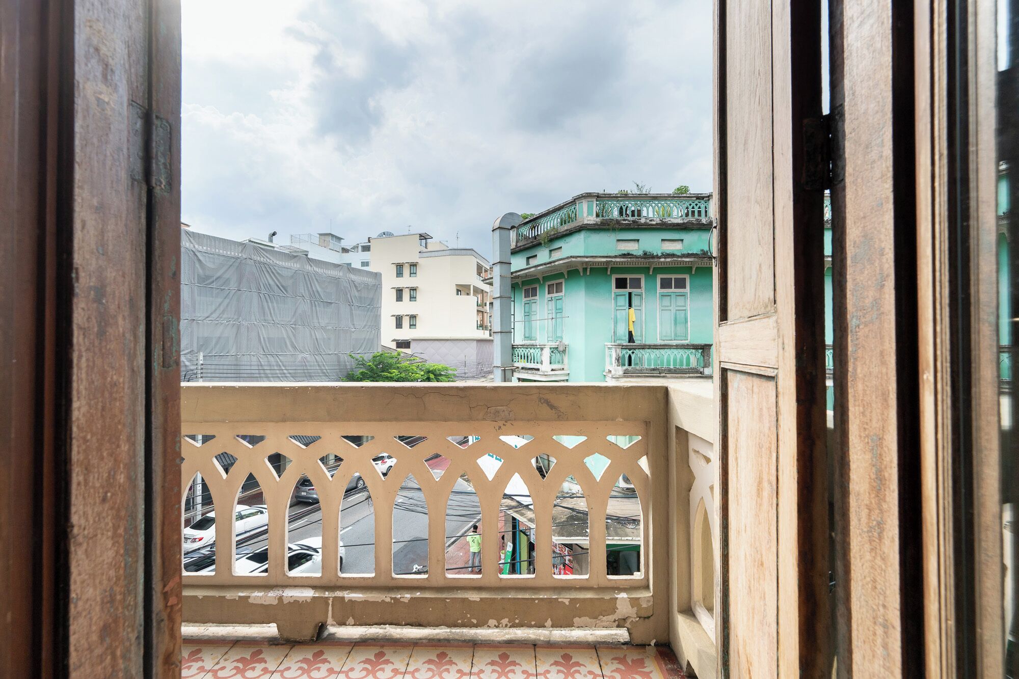 A balcony with a view of a cityscape, including a turquoise building and other residential structures.