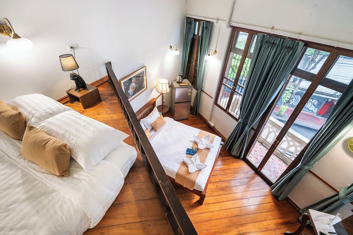 Hotelkamer met een bed, een bureau, een stoel, een tafeltje, een lamp, een fotolijst en een raam met gordijnen.