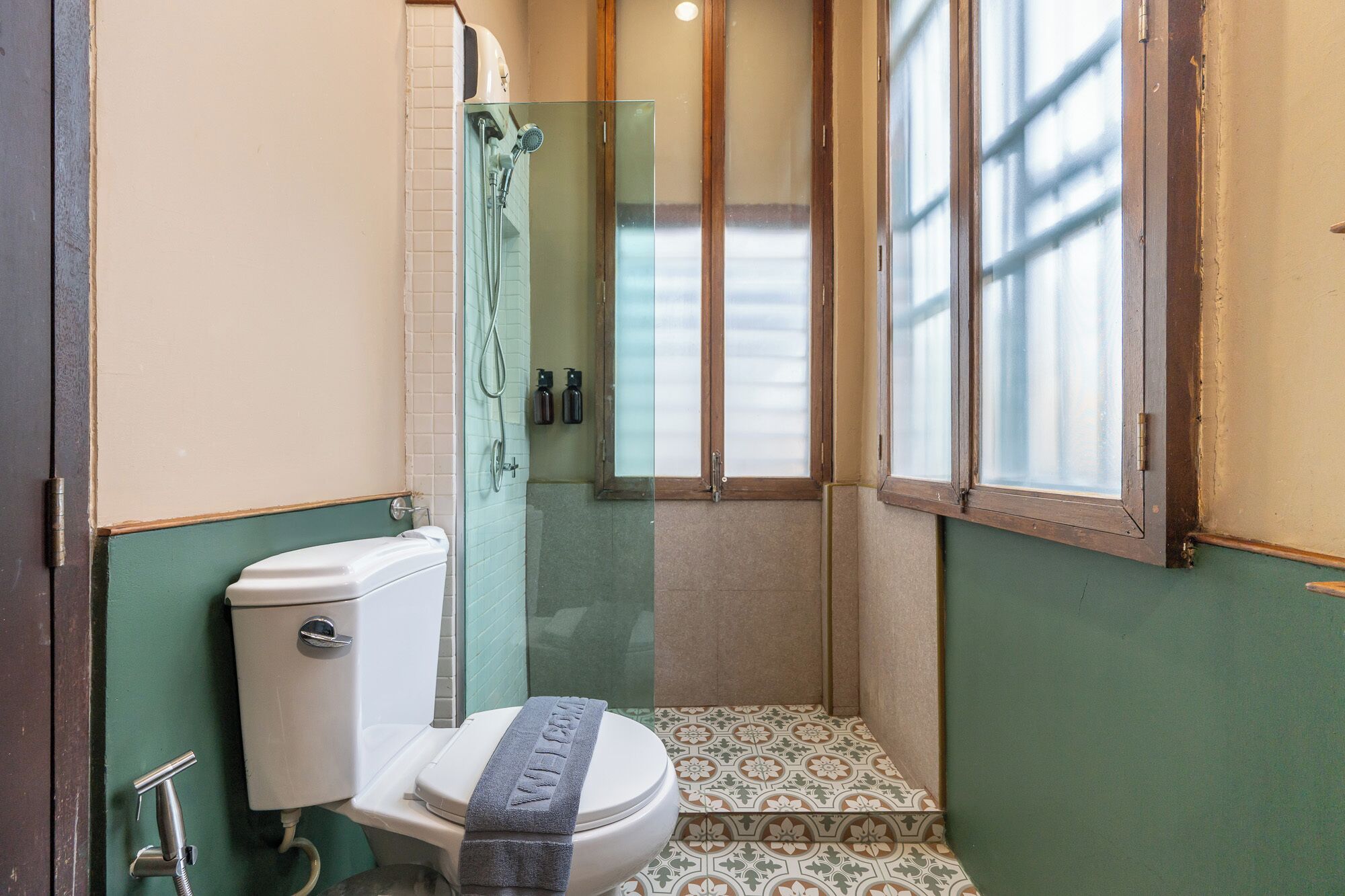 Een kleine badkamer met toilet, douche en raam.