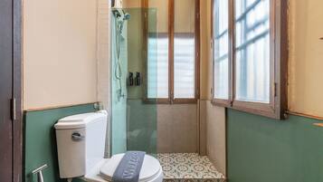 Een kleine badkamer met toilet, douche en raam.