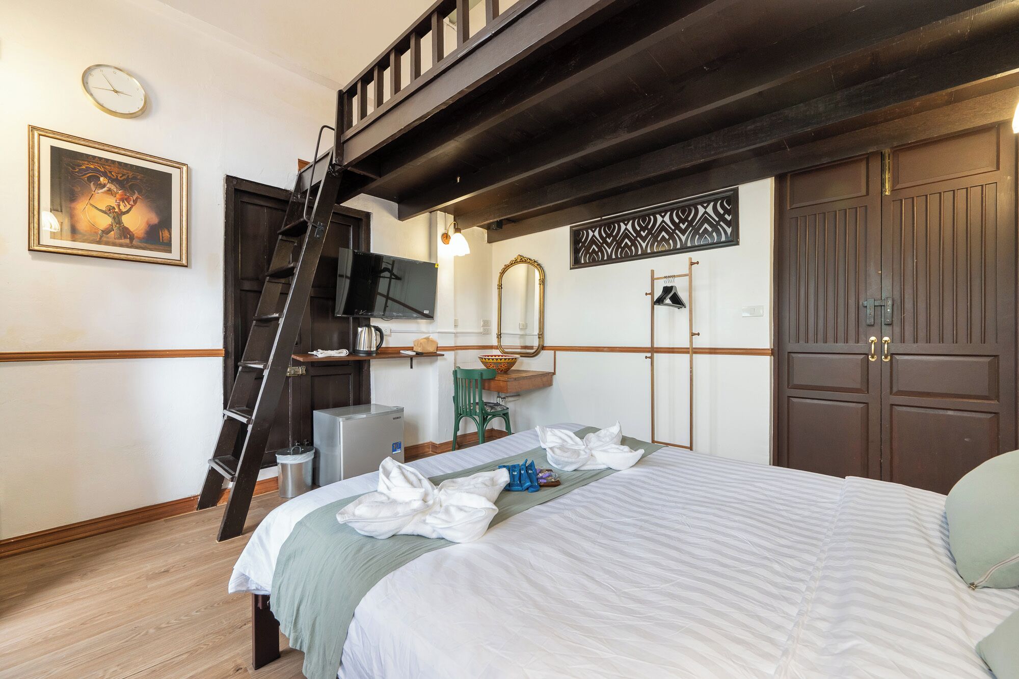 Un dormitorio con cama, televisión, espejo, cómoda, silla y escalera.