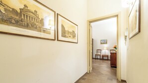 A hallway with framed historical photographs on the walls, a wooden floor, and a door leading to a room with a desk and chairs. - 3 House by Ghor (Rome)