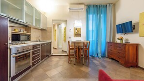 A modern kitchen with a dining area, a TV, and a wooden cabinet. - 3 House by Ghor (Rome)