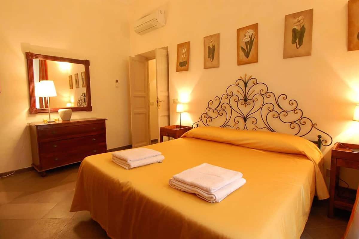 A hotel room with a bed, a dresser, a mirror, and wall art.