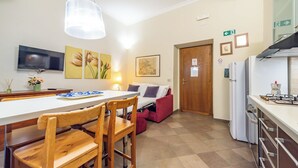 A compact kitchen with a dining area, a TV mounted on the wall, and a small refrigerator. - 3 House by Ghor (Rome)
