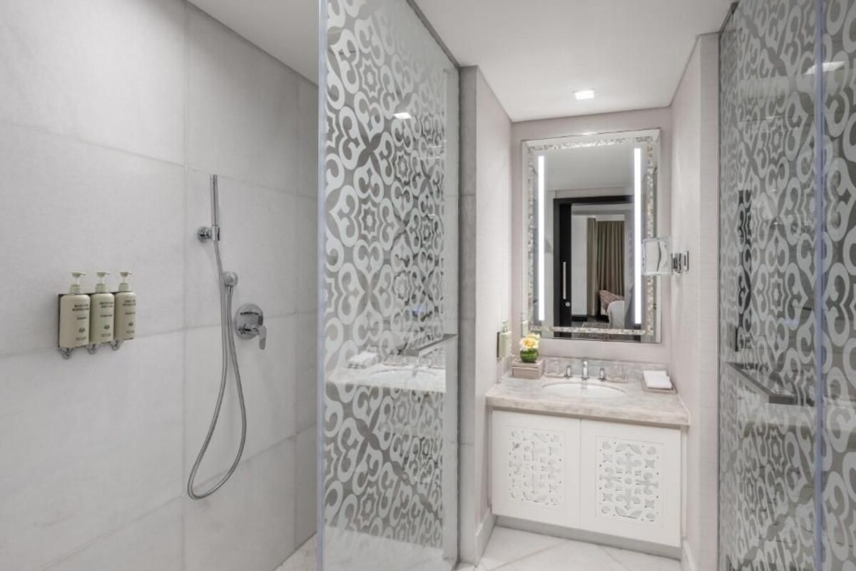A modern bathroom with a shower, vanity, and a large mirror.