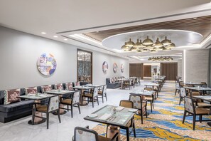 A modern dining area with booths and tables, decorative wall art, and a patterned carpet.