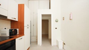 A narrow kitchen with white cabinets, a microwave, and a black oven. - Rafael House by Ghor (Rome)