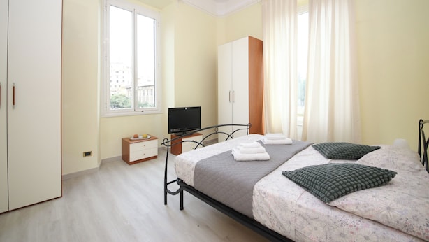 A bedroom with a bed, a television, a wardrobe, and a window. - Rafael House by Ghor (Rome)