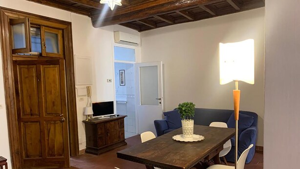 Ein Essbereich mit einem Holztisch, weißen Stühlen, einer blauen Couch und einer Stehlampe.