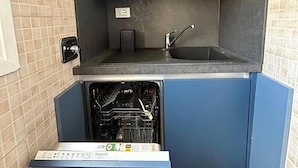 A compact kitchen with blue cabinets, a built-in dishwasher, and a small countertop. - Manzoni Blue House by Ghor (Rome)