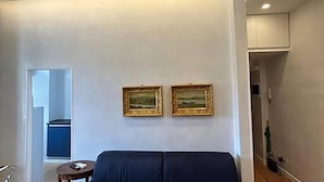 A modern living room with a dark blue sofa, two framed pictures on the wall, and recessed ceiling lights. - Manzoni Blue House by Ghor (Rome)