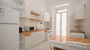 A modern kitchen with white cabinets, a microwave, a coffee maker, and a dining table with chairs. - Rome Flat 42 by Ghor (Rome)