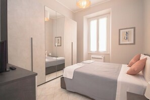 A modern bedroom with a large bed, a bedside table, a mirror, and a window. - Rome Flat 42 by Ghor (Rome)