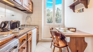 Une cuisine avec des meubles en bois, un plan de travail équipé d’appareils électroménagers, une fenêtre donnant sur un beau paysage et une table à manger avec des chaises.