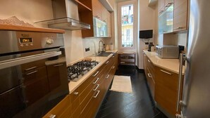 A modern kitchen with stainless steel appliances, wooden cabinets, and a black tiled floor. - Domus Parioli by Ghor (Rome)