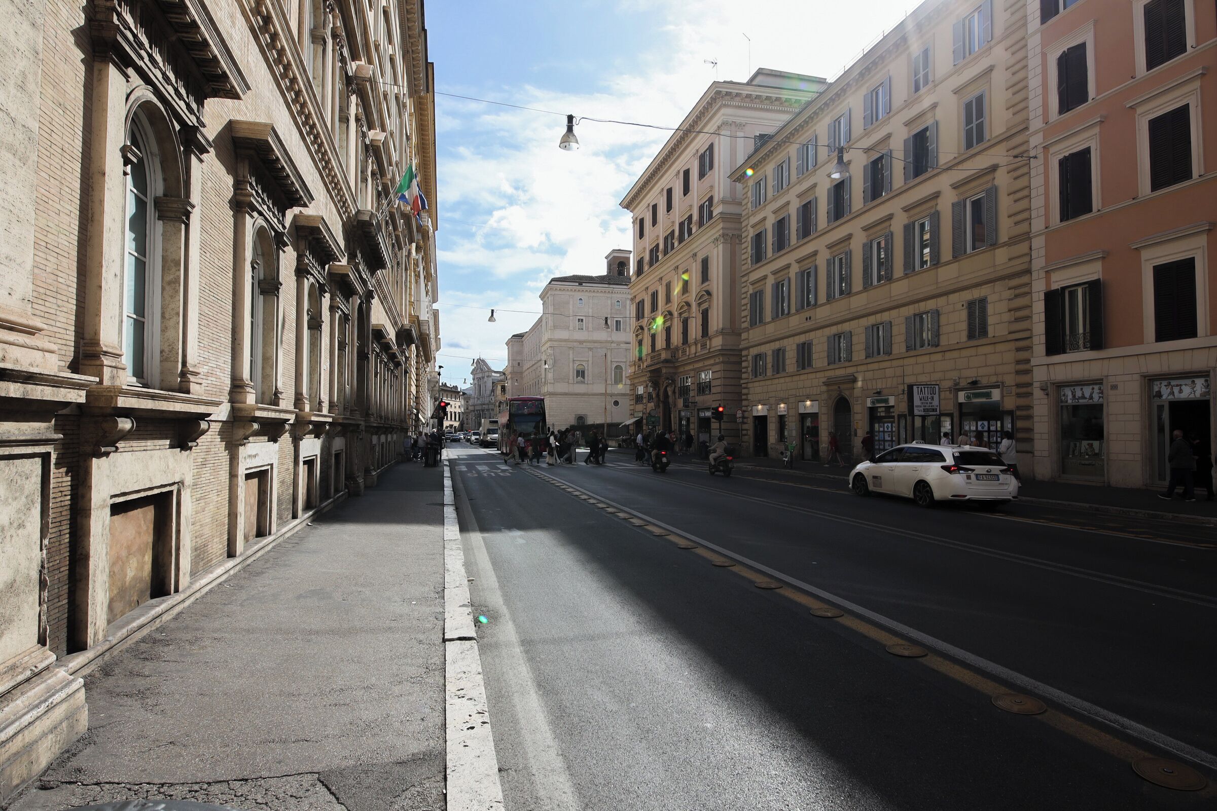 A street with historic buildings, a clear sky, and a white car parked on the side.