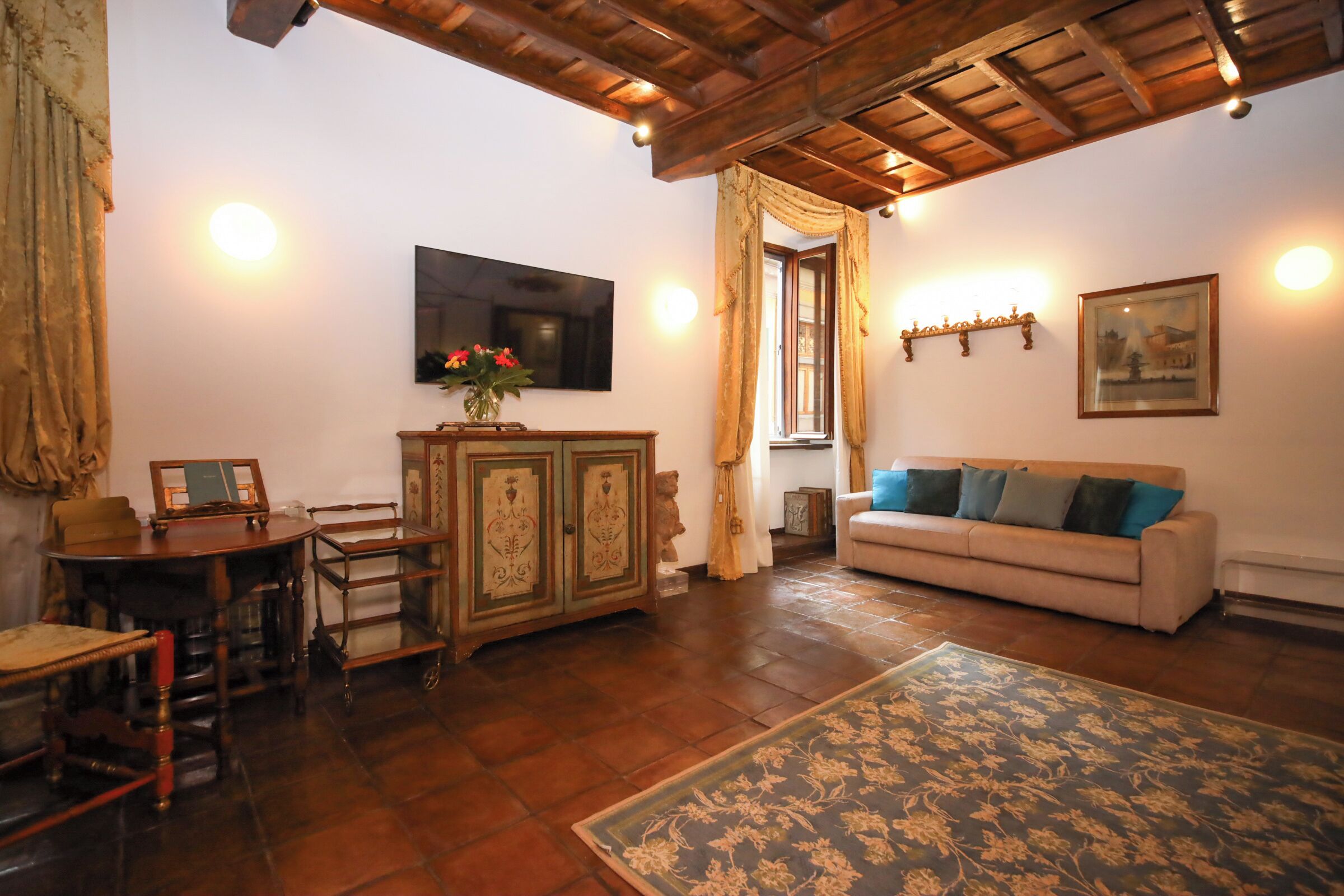 A living room with a wooden ceiling, a sofa, a TV, a cabinet, and a patterned rug.