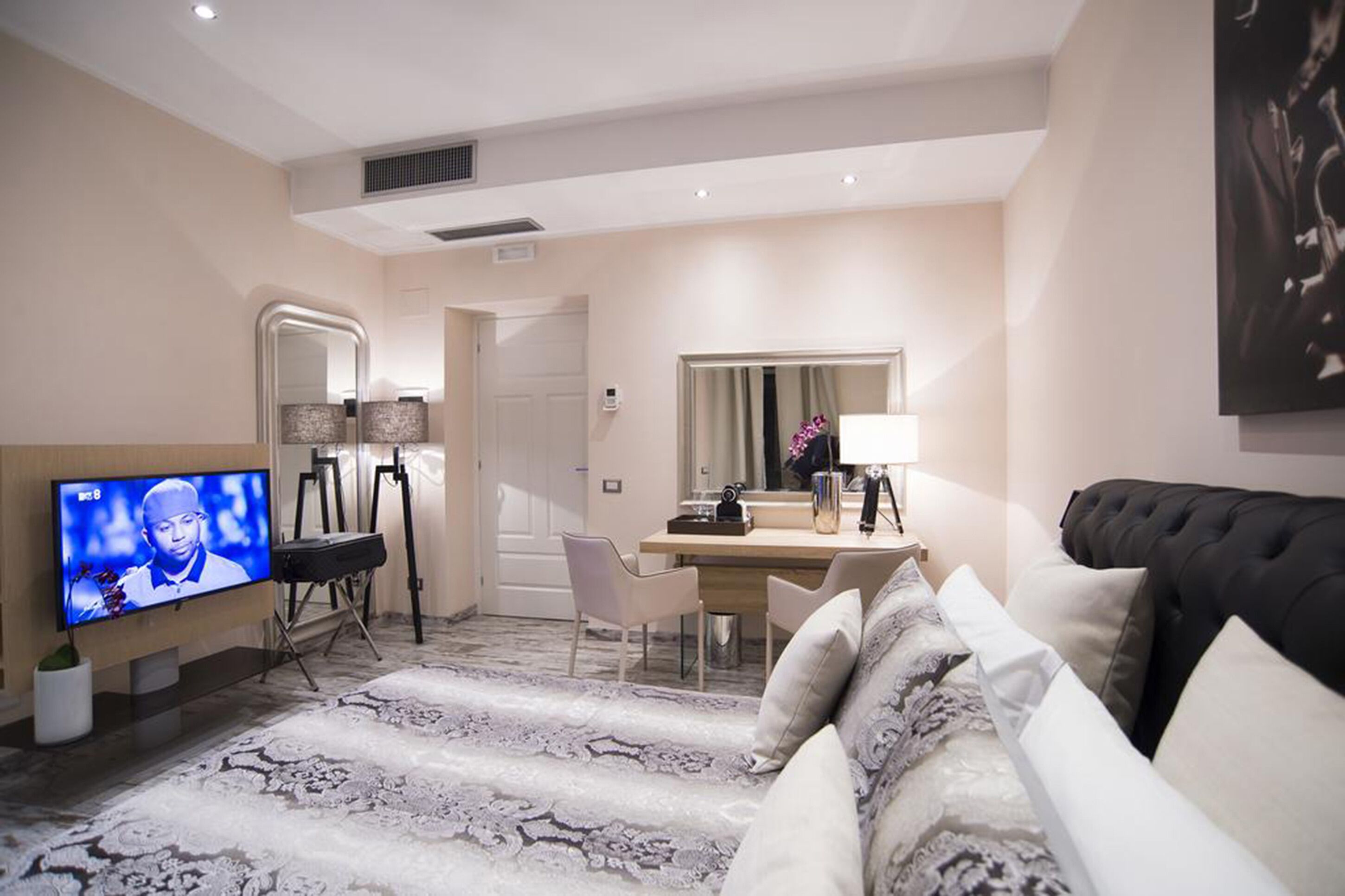 A modern living room with a flat-screen TV, a dining area with a table and chairs, a sofa, and a large mirror.