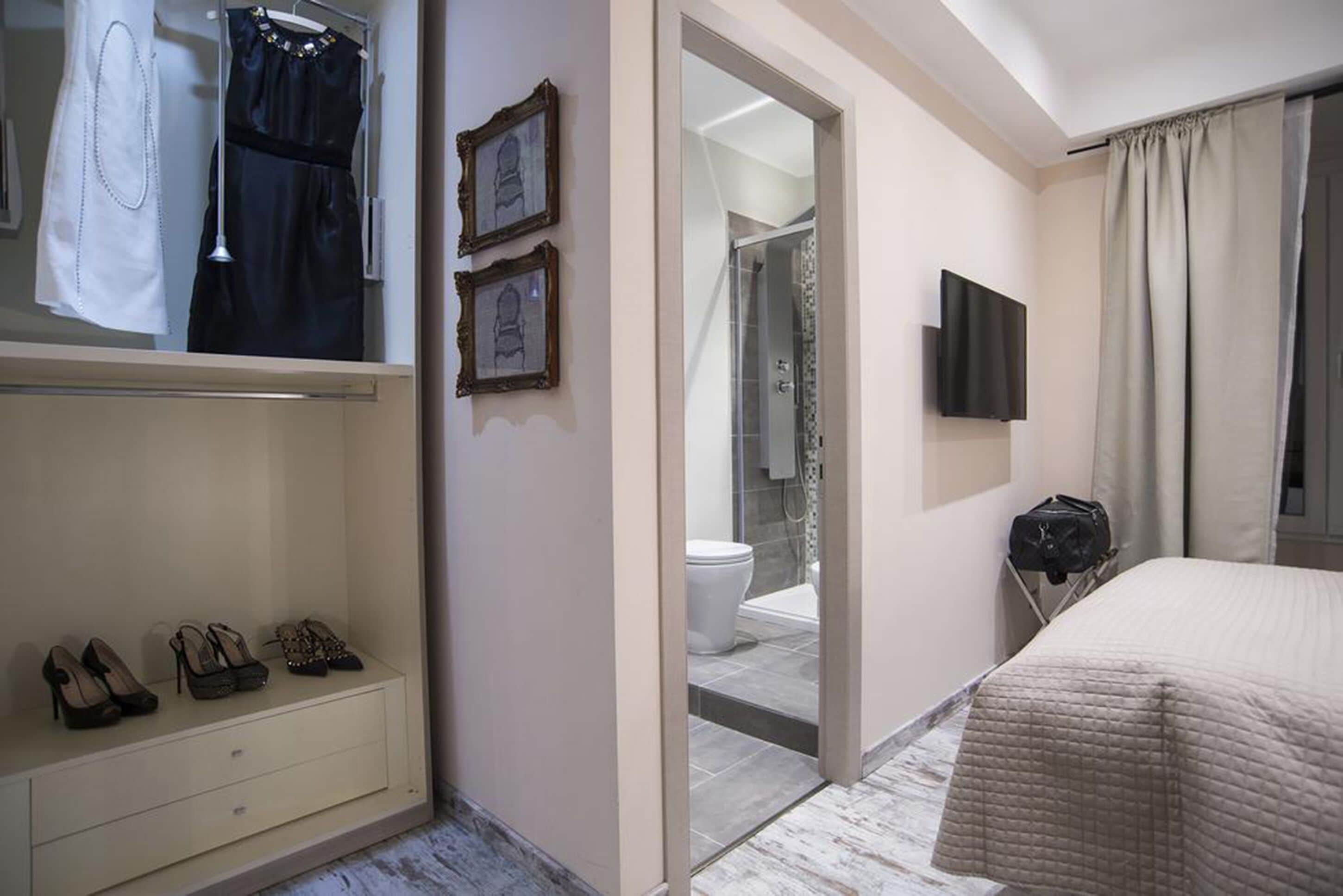 A hotel room with a bed, a TV, a wardrobe, and a bathroom visible through an open door.