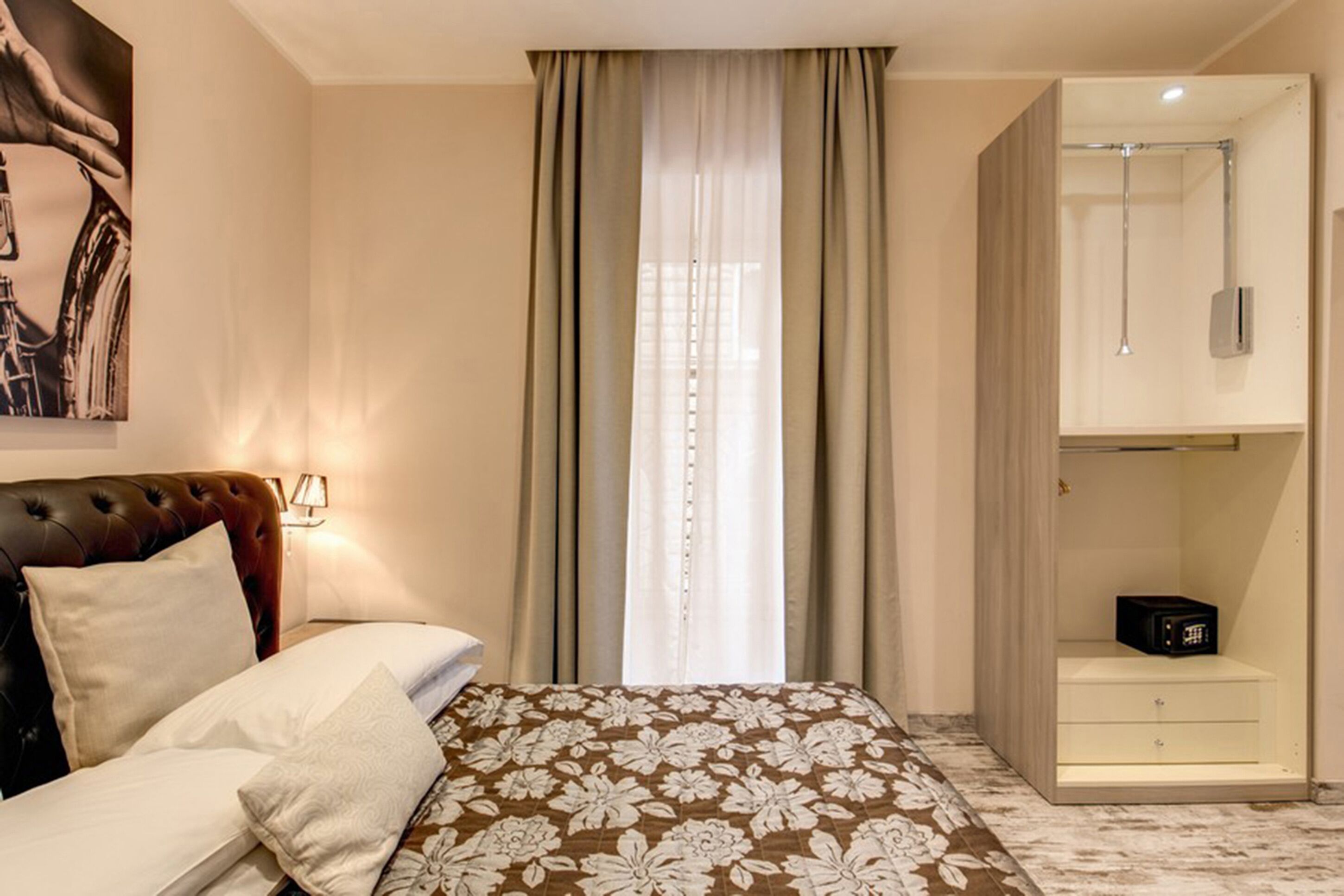 Una camera d'albergo con un letto, un armadio, un comodino e un quadro appeso al muro.