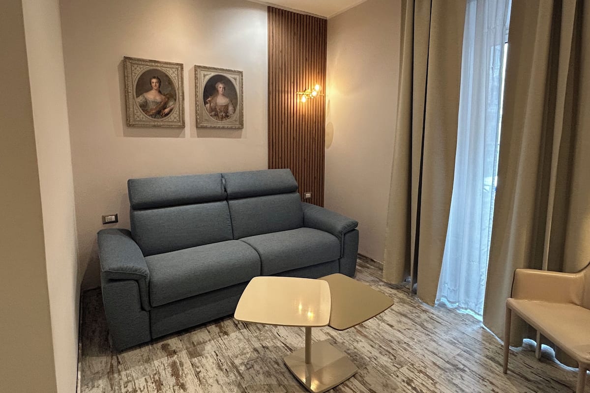 Una sala de estar moderna con un sofá gris, una mesita y dos cuadros en la pared.