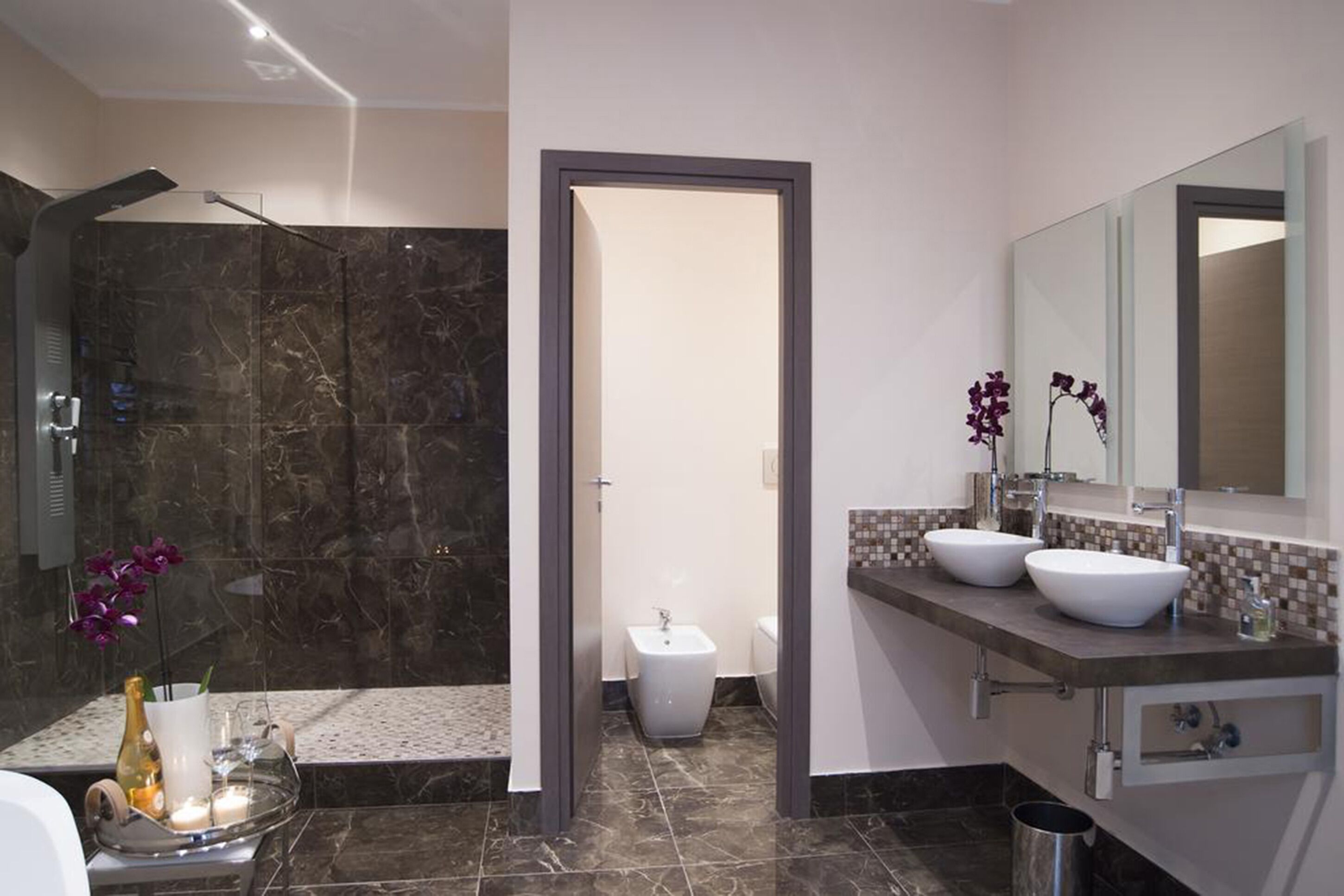 Une salle de bain moderne avec deux lavabos, un grand miroir et un espace douche.