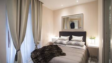 Um quarto moderno com uma cama grande, uma mesa de cabeceira, um espelho e uma janela com cortinas.