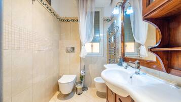 Ein Badezimmer mit Toilette, Bidet, Waschbecken, Spiegel und Duschvorhang.