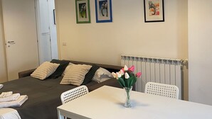 Ett hotellrum med en säng, ett bord med en vas med blommor och tre inramade tavlor på väggen.