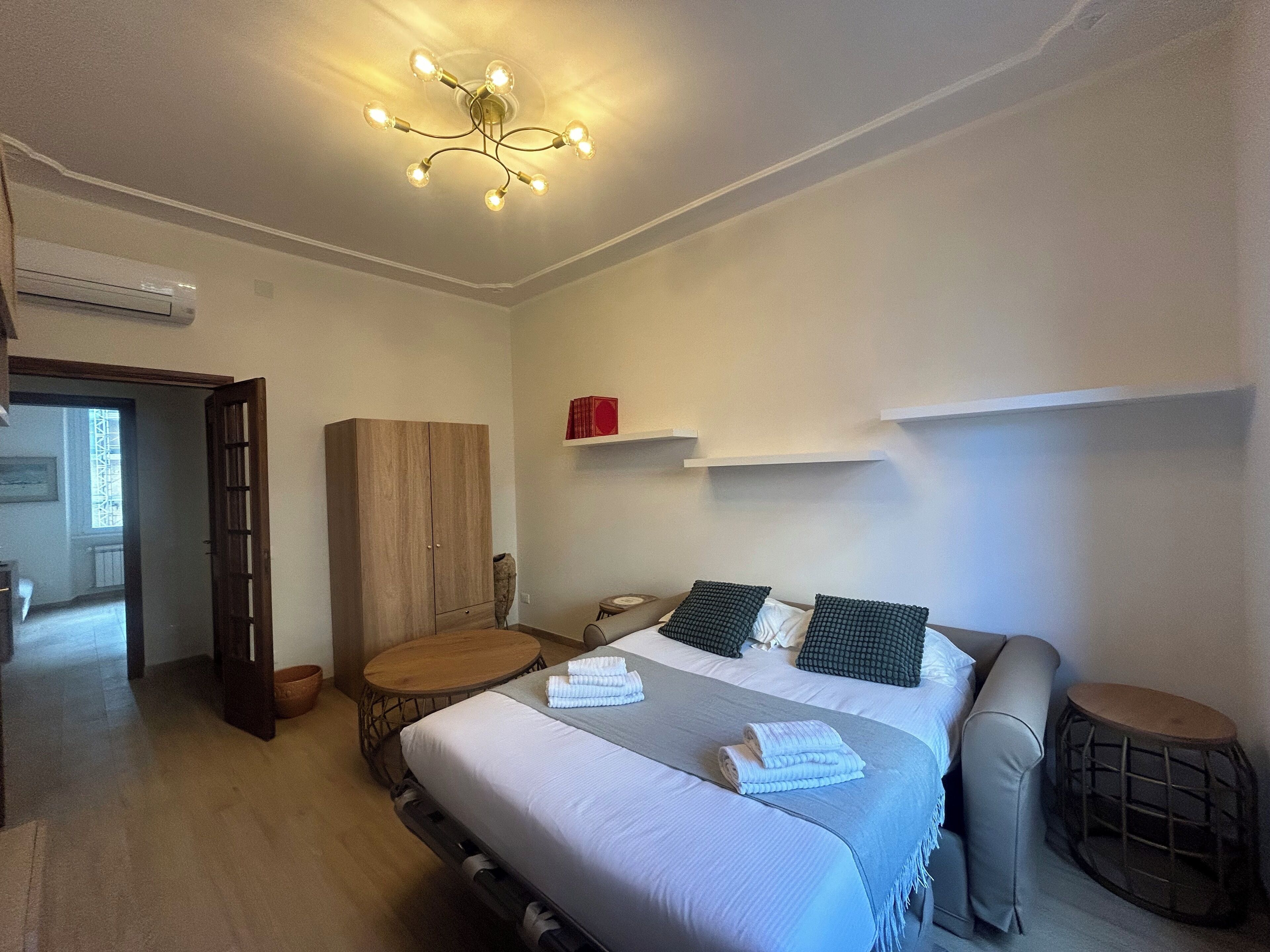 Une chambre à coucher comprenant un lit, des tables de chevet, une armoire et un luminaire au plafond.