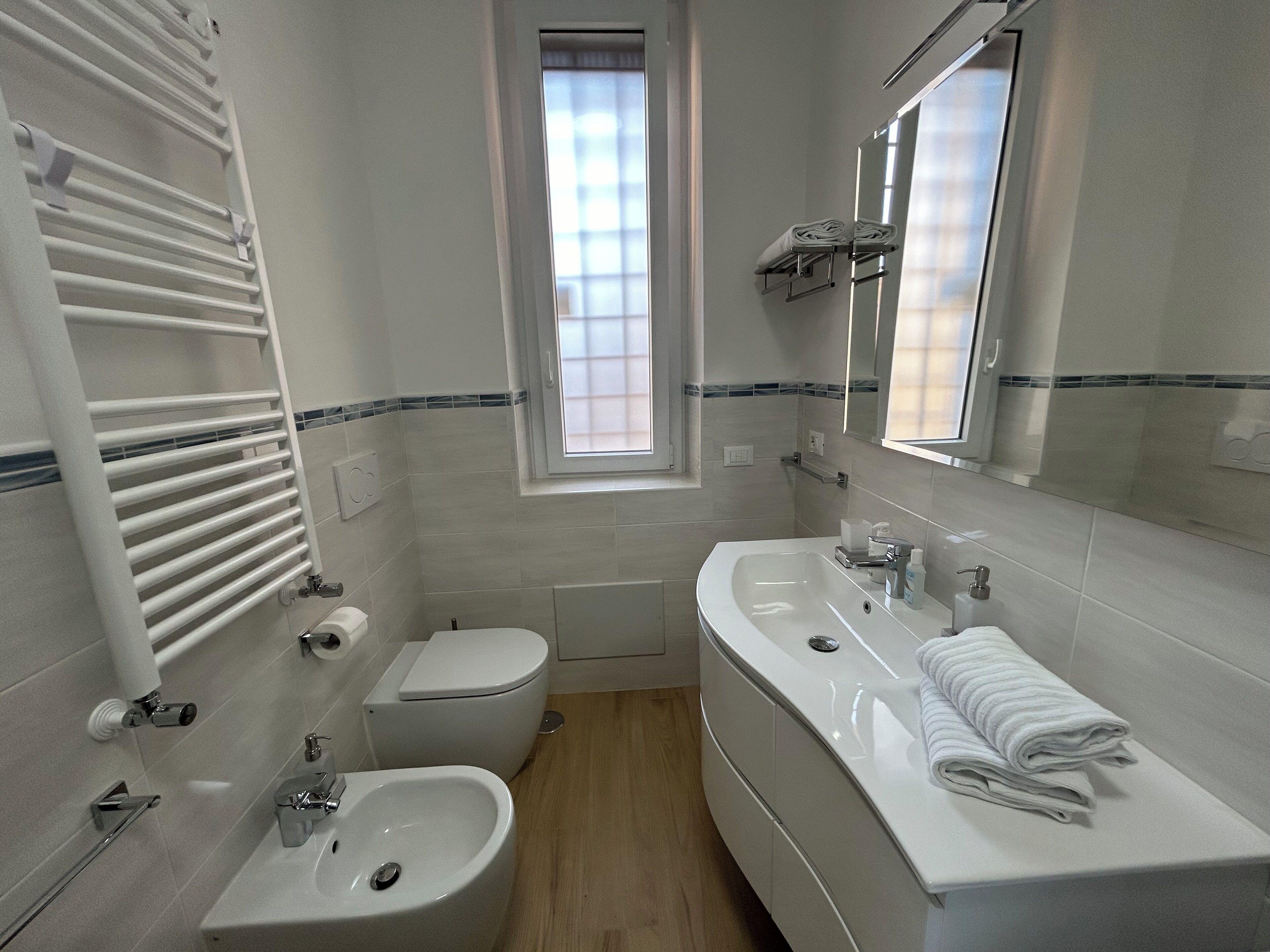 A modern bathroom with a toilet, bidet, sink, and a mirror.