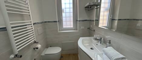 A modern bathroom with a toilet, bidet, sink, and a mirror.