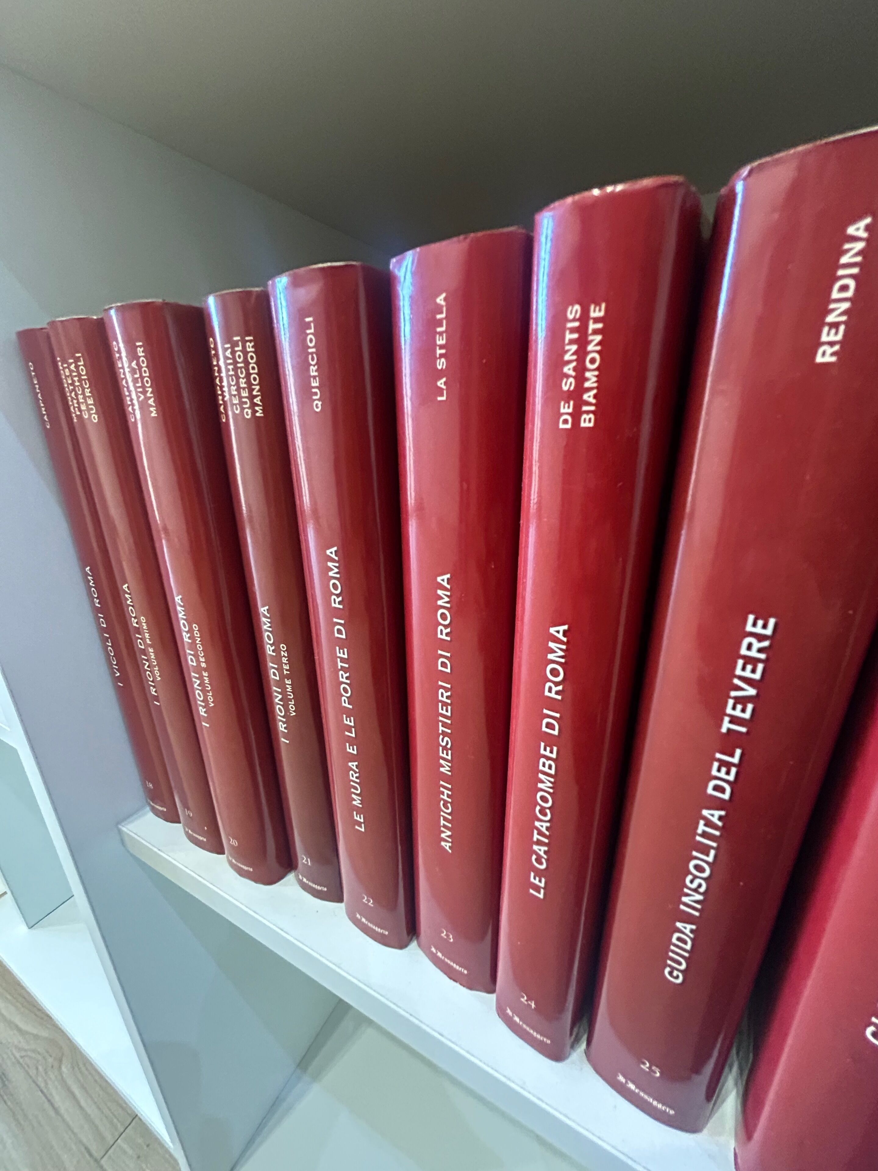A row of red books on a white shelf.