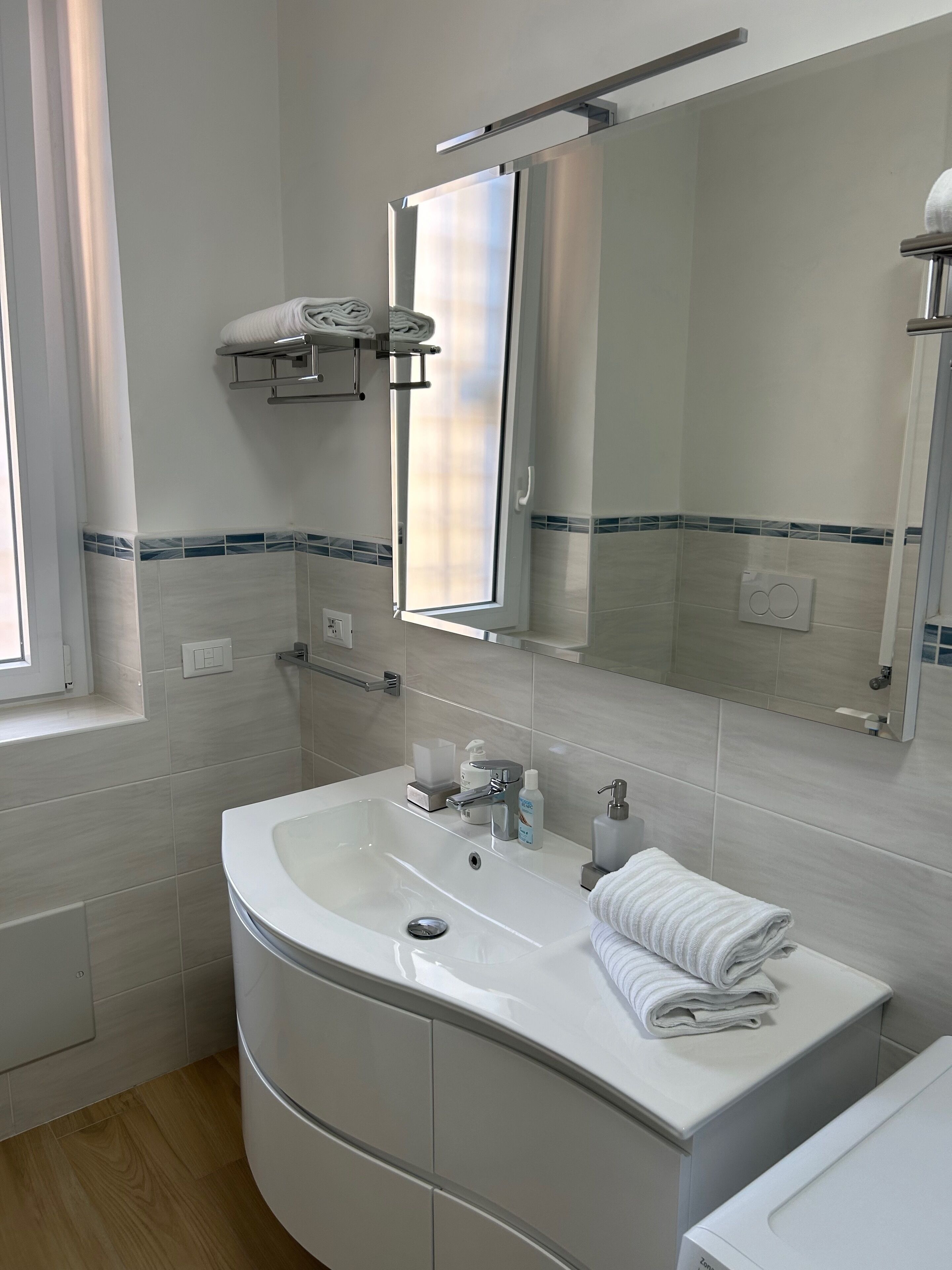 Een moderne badkamer met een wit wastafelmeubel, spiegel en handdoekhouder.